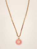 Pink Chanel necklace with gold chain on a light pink background